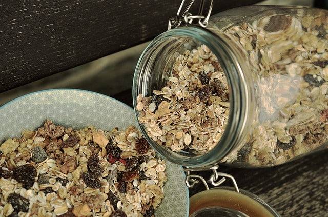 Bio-Müsli wird von Einmachglas in Schüssel umgefüllt