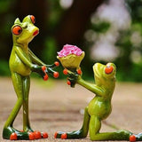 Kniender Frosch überreicht stehendem Frosch einen Blumenstrauß.